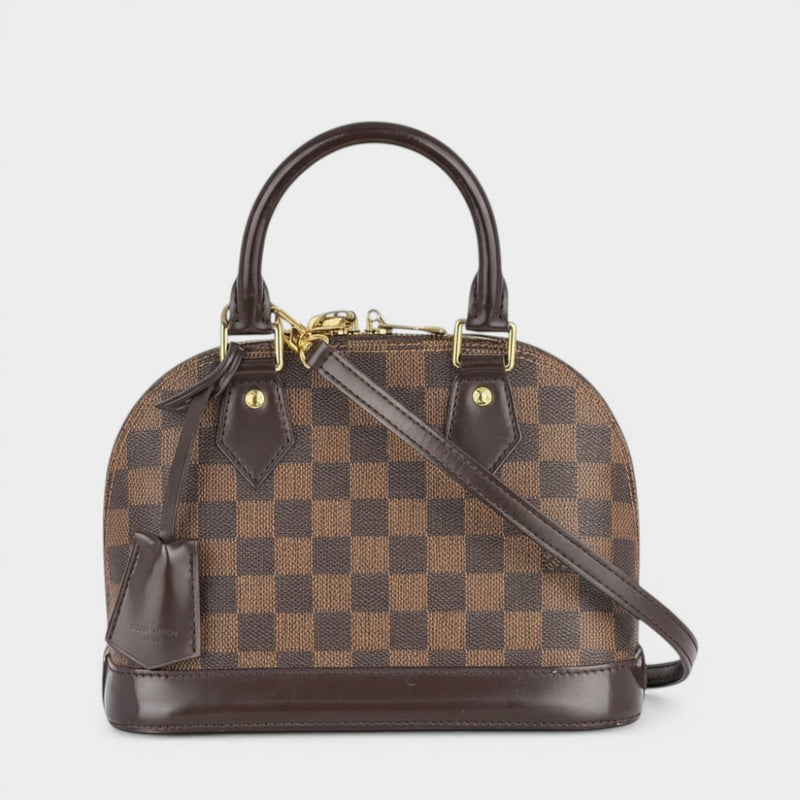 Secondtimearound Louis Vuitton Alma mini bag in brown Damier Ebene canvas with leather trim and gold hardware.